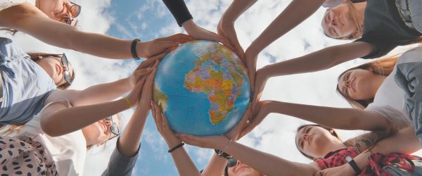 Earth conservation concept. 11 girls hug the earth globe with their hands